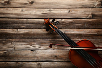 Violin with bow on brown wooden table