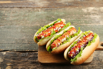 Hot dogs with ketchup, mustard and vegetables on wooden table