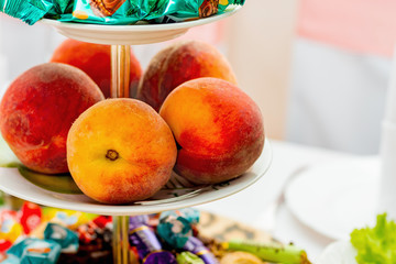 Fresh juicy peaches in a plate at the restaurant's festive table_