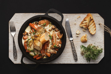 Meat and vegetable casserole on wooden board, top view