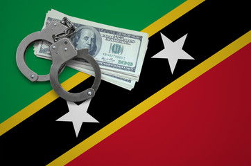 Saint Kitts and Nevis flag  with handcuffs and a bundle of dollars. The concept of breaking the law...