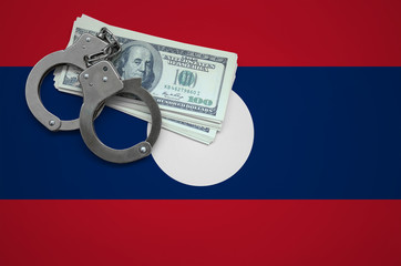 Laos flag  with handcuffs and a bundle of dollars. The concept of breaking the law and thieves...