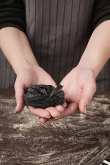 Woman making tagliatelle nest on kitchen table