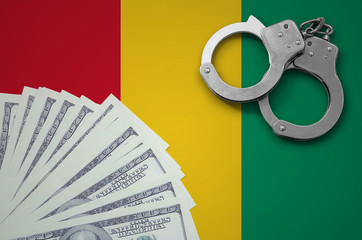Guinea flag  with handcuffs and a bundle of dollars. The concept of illegal banking operations in...