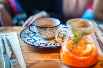 Summer tea in a large pot with a sprig. Tea with mango and orange on the table in a cafe