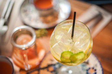 Summer cocktail in a large glass with lemon, cucumber. Summer sangria on the table in a cafe