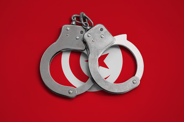 Tunisia flag  and police handcuffs. The concept of observance of the law in the country and...