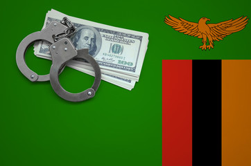 Zambia flag  with handcuffs and a bundle of dollars. The concept of breaking the law and thieves...