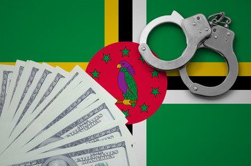 Dominica flag  with handcuffs and a bundle of dollars. The concept of illegal banking operations in...
