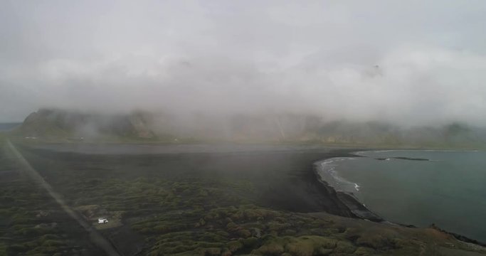 arial drone view stokksnes with vestrahorn covered in clouds in iceland reverse tracking shot
