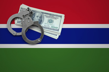 Gambia flag  with handcuffs and a bundle of dollars. The concept of breaking the law and thieves...