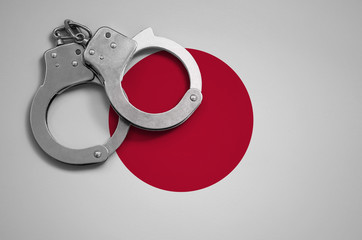 Japan flag  and police handcuffs. The concept of crime and offenses in the country