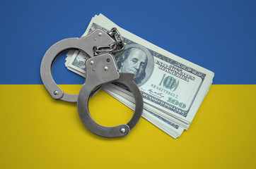 Ukraine flag  with handcuffs and a bundle of dollars. Currency corruption in the country. Financial crimes