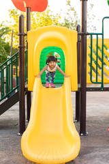 little girl having fun to play slider in the playground in summer time