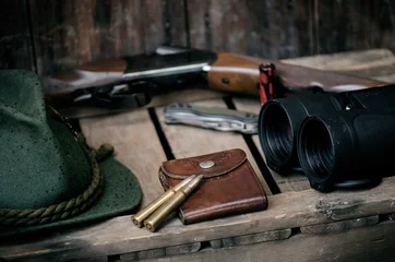 Poster Professionele jagersuitrusting voor de jacht. Detail over de munitie. Houten zwarte achtergrond met geweer, hoed en andere uitrusting voor de jacht. © tibor13
