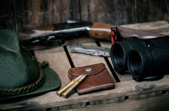 Professional hunters equipment for hunting. Detail on the ammunition.  Wooden black background with rifle, hat, and other equipment for hunting. 