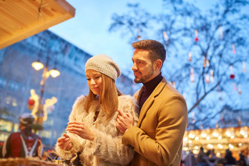 A beautiful young couple smiling and checking the gifts in a christmas market.