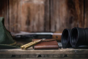 Stickers pour porte Chasser Équipement de chasseur professionnel pour la chasse. Détail sur les munitions. Fond noir en bois avec fusil, chapeau et autres équipements de chasse.