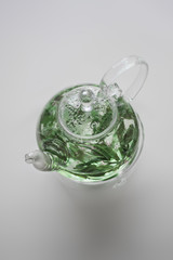 Glass Teapot with Green Tea on White 