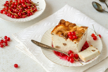 Sweet dessert. Homemade pudding from cottage cheese with raisins and fresh red currant berries on a round dessert plate on the table.