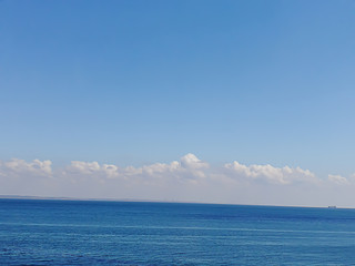 Naklejka na ściany i meble background of beautiful blue black sea under fluffy white clouds under the blue sky