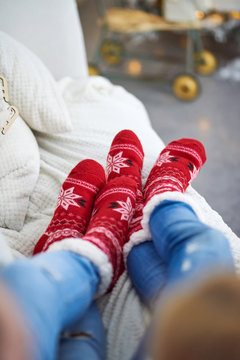 A Couple Laying On The Sofa And Wearing Red Christmas Themed Socks.