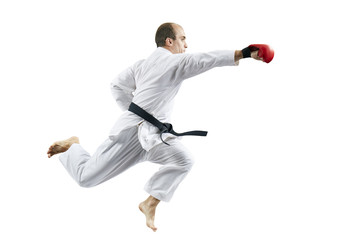 Male athlete strikes with a hand jumping against a white background