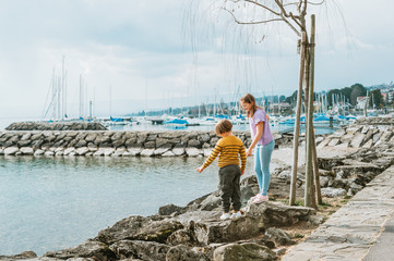 Two funny kids, little brother and sister, playing together outside by the lake