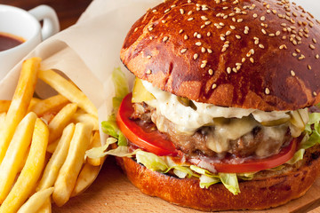 Beef burger and french fries on wooden cutting board