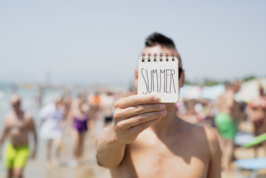 man shows a note with the text summer
