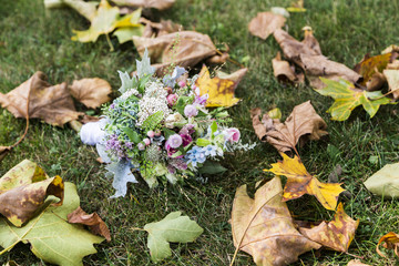 Bouquet of orchids and roses lying on grass near maple leaves