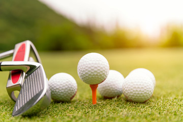 Golf balls and golf club on green grass