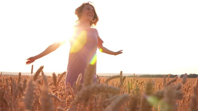 Beautiful woman spinning around in wheat field