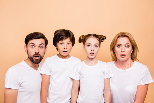 Closeup portrait of young family, bearded father, blonde mother and their little children, boy and girl, wearing white T-shirts showing surprising on camera on beige background