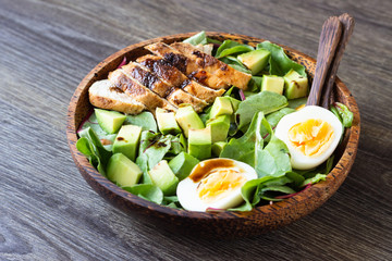 Green lunch bowl with grilled chicken, avocado and eggs. Healthy and dietary food. Space for text.