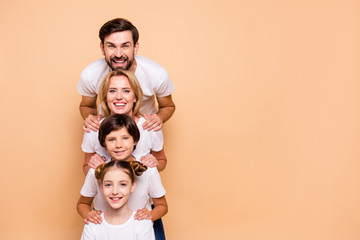 Young smiling family, bearded father, blonde mother, boy and girl wearing white T-shirts, standing...