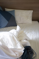 Fototapeta na wymiar Crumpled bed sheet and pillows after comfort duvet sleep waking up
