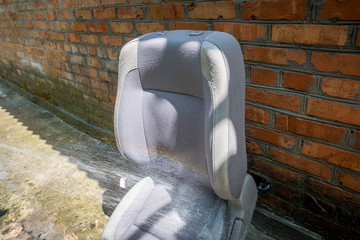 washing the car seat at home by spraying water from the hose in the courtyard of the house
