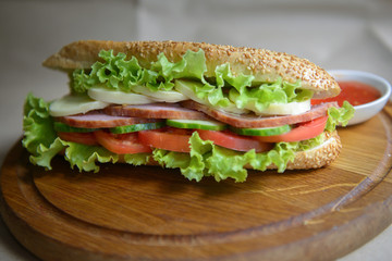 Sandwich with cheese, ham and sauce on the kitchen board