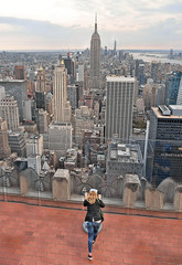 young woman watching a new york cityscape and skyline Rockefeller Center Observatory in manhattan...