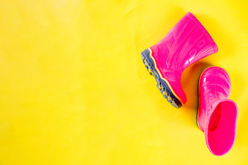 Autumn kids cloth concept, bright pink rubber boots for rain, top view