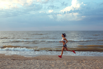 Obraz na płótnie Canvas healthy young fitness woman trail runner running on sunrise seaside