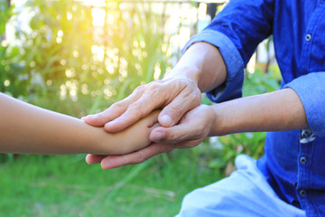 Take care, Senior man holding hands of Little child girl on natural green background
