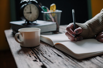 Close up of woman's hands writing on book, vintage color tone