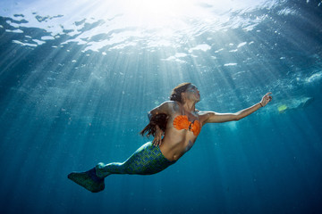 Mermaid swimming underwater in the deep blue sea