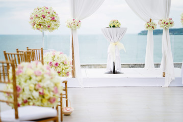 Wedding arch and altar decorated with white lawn fabric and roses, flowers, floral and green leaf with ocean view background