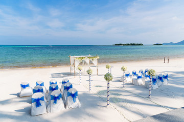 Wedding ceremony venue on the beach with beautiful blue sky and ocean view, White cover chairs with...