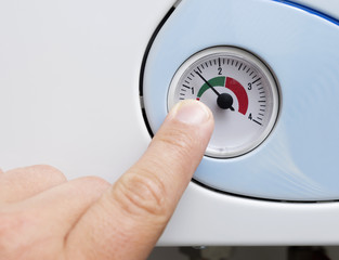 Man's hand adjusts the heating boiler