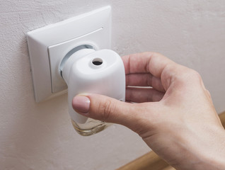 Woman's hand with an electric anti mosquito diffuser, repellent.