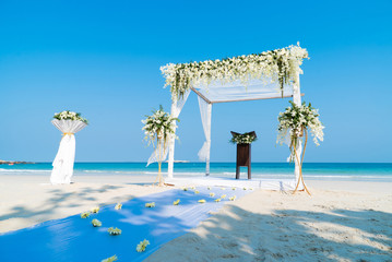 Close-up beautiful beach wedding arch setting with white flowers and green leafs decoration, panoramic nature sea view